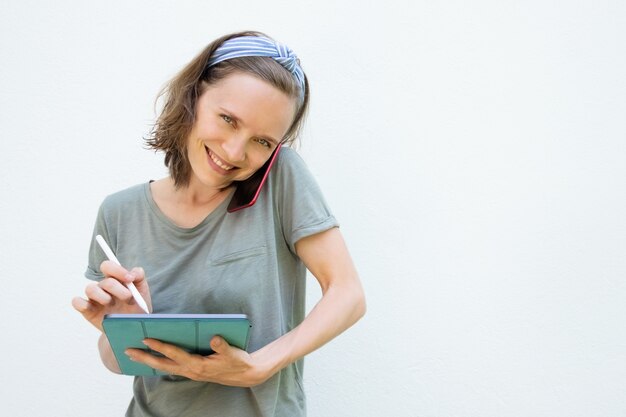 Alegre mulher encantada, escrevendo na tela do tablet