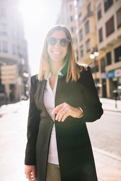 Alegre mulher jovem elegante com óculos de sol na rua