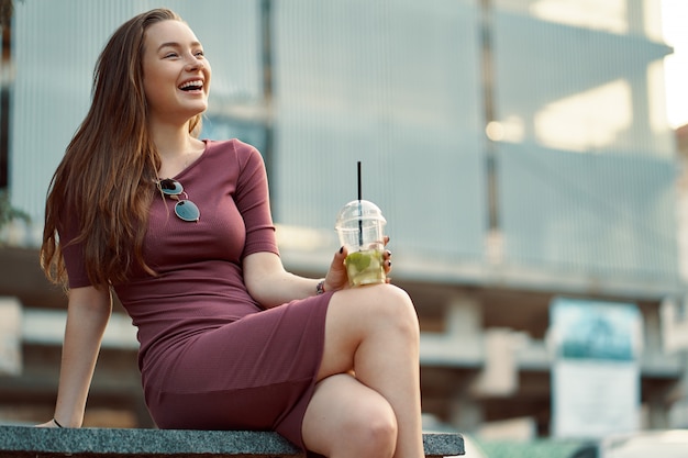 Foto grátis alegre mulher na rua bebendo bebida refrescante de manhã