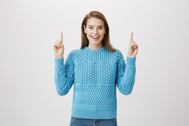 Alegre mulher sorridente apontando os dedos para cima