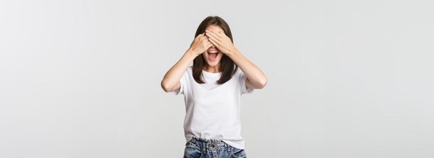 Alegre mulher sorridente fecha os olhos e espera surpresa