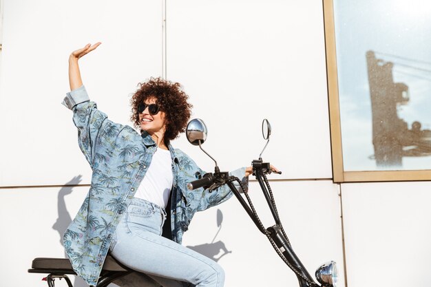 Alegre mulher sorridente, sentado em uma moto moderna