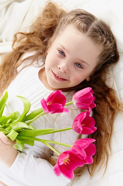 Alegre pequena menina, segurando flores