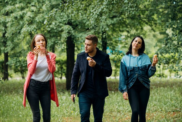 Alegres amigos andando no parque com sorvete