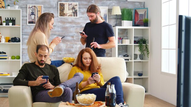 Alegres amigos caucasianos jogando videogame na grande tv na sala de estar.