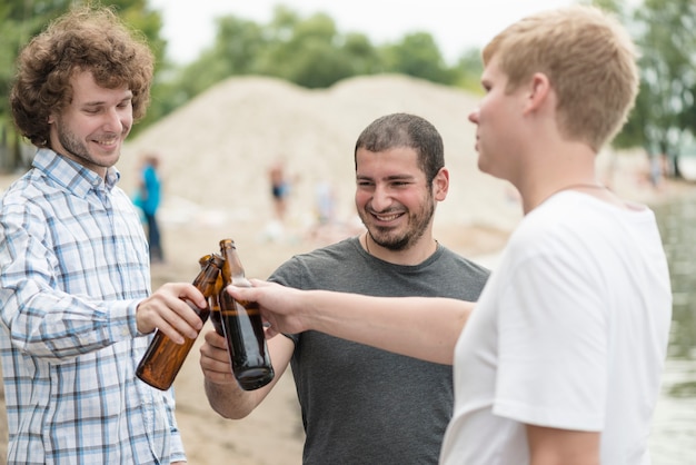 Alegres amigos tinindo garrafas na praia