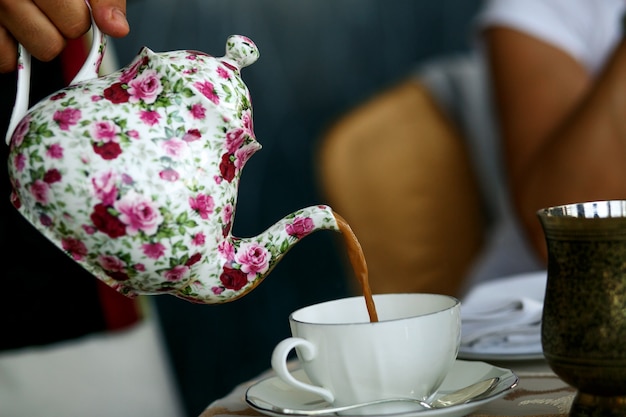 Foto grátis alguém derrama chá em copo branco de porcelana