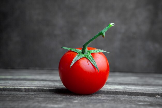 Algum tomate no fundo de madeira e textured escuro, vista lateral.