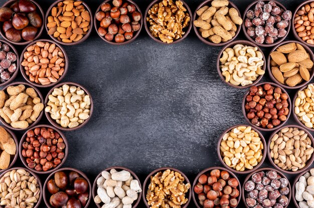 Algumas nozes sortidas e frutas secas com nozes, pistache, amêndoa, amendoim, em uma mini tigelas diferentes