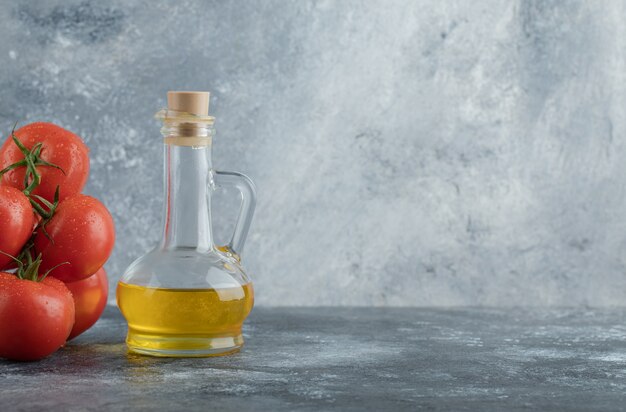 Alguns tomates suculentos com uma garrafa de vidro de óleo.