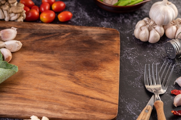 Alho, tomate, tábua de cortar e garfo de cozinha.