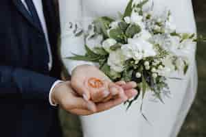 Foto grátis alianças nas mãos da noiva e do noivo e com um lindo buquê de flores e flores brancas