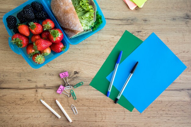 Almoço em recipiente e cadernos na mesa