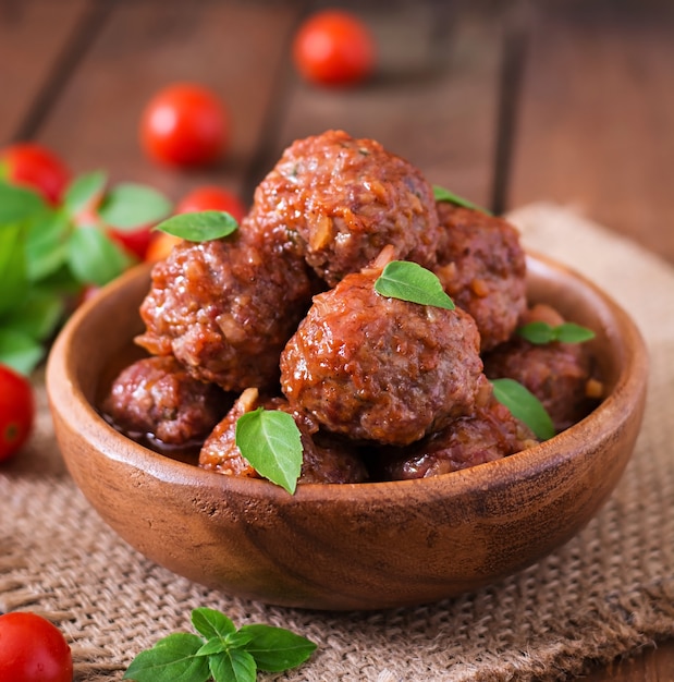 Almôndegas em molho de tomate agridoce e manjericão em uma tigela de madeira