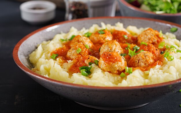 Almôndegas em molho de tomate com purê de batatas na tigela.