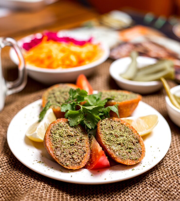 Foto grátis almôndegas recheadas turcas ichli kofte servido com limão tomate e salsa