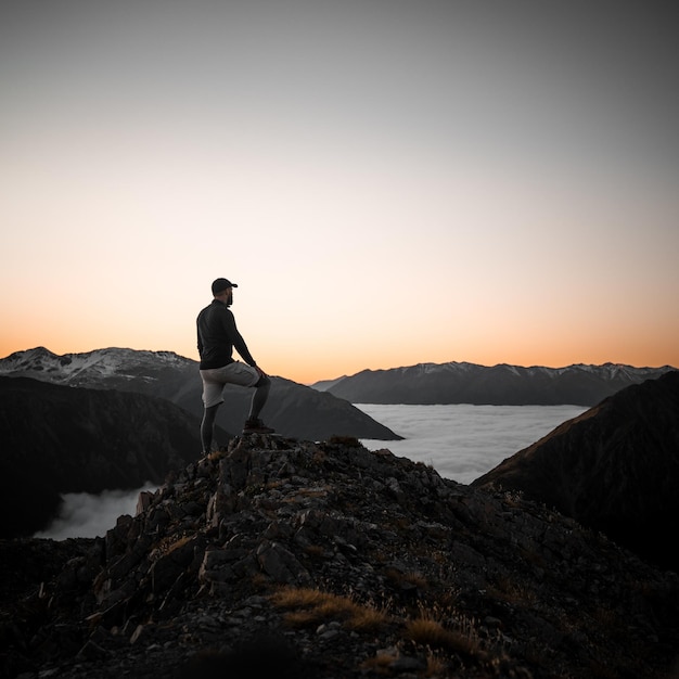 Foto grátis alpinista caucasiano adulto em pé em uma colina durante o pôr do sol na lituânia