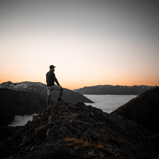 Alpinista caucasiano adulto em pé em uma colina durante o pôr do sol na Lituânia