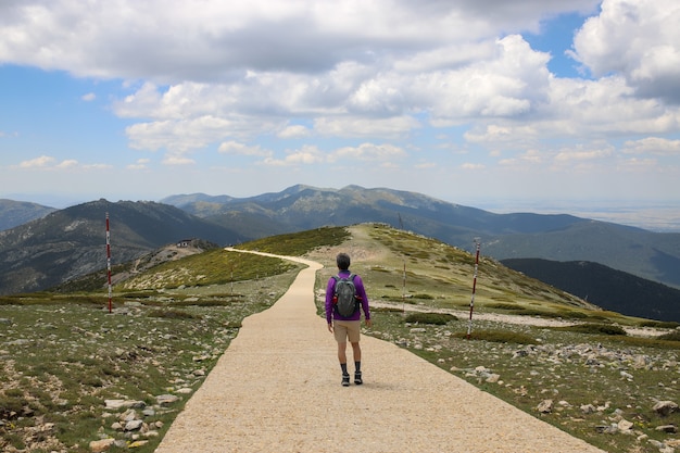 Alpinista com uma mochila caminhando por uma estrada em uma colina coberta de vegetação - conceito de sucesso