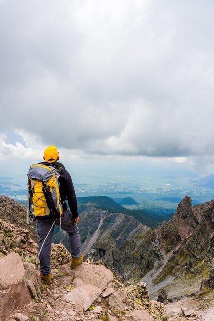 Alpinista com uma mochila em pé no topo da montanha