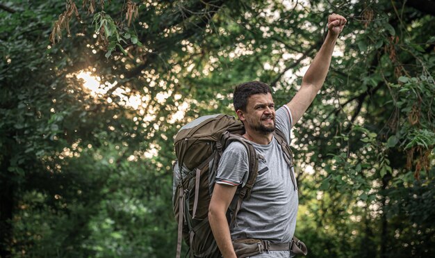 Alpinista em uma caminhada com uma grande mochila em um fundo desfocado da floresta.