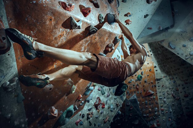 Alpinista livre escalando pedra artificial dentro de casa