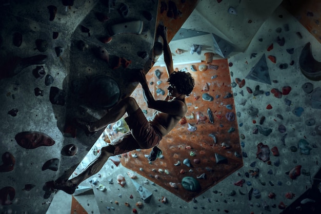 Foto grátis alpinista livre escalando pedra artificial dentro de casa