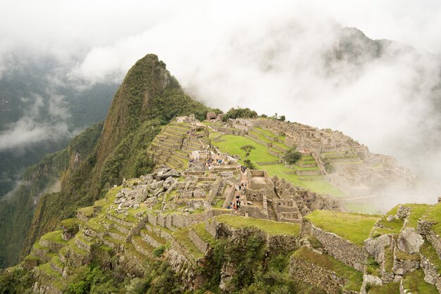 Alto ângulo da bela cidadela de Machu Picchu, rodeado por montanhas nubladas em Urubamba, Peru
