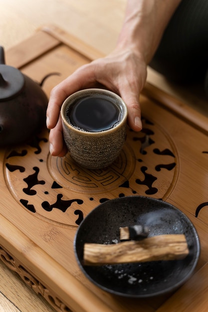 Alto ângulo das mãos de uma mulher com uma xícara de chá e uma chaleira