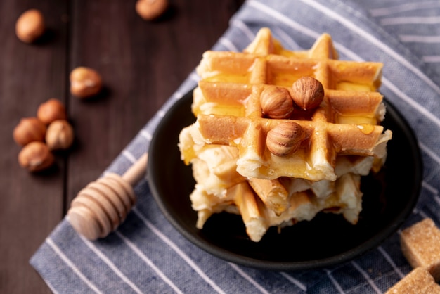 Alto ângulo de avelãs e mel em cima de waffles no prato