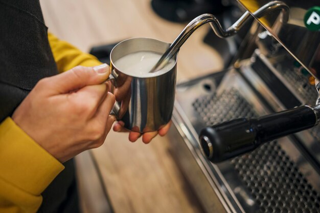 Alto ângulo de barista espumando leite