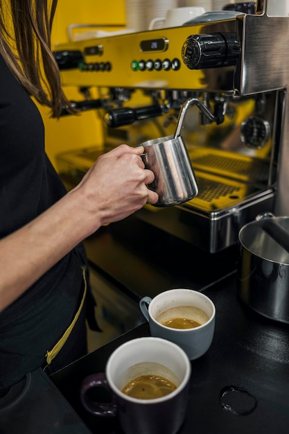 Alto ângulo de barista feminino espumando leite