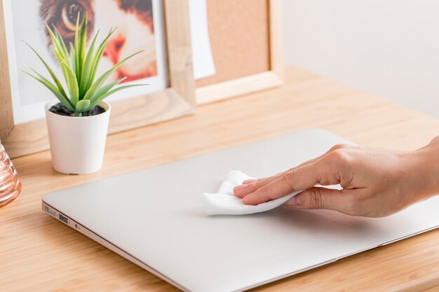 Alto ângulo de mão desinfetar laptop na mesa