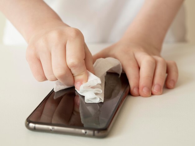 Alto ângulo de mãos desinfetando smartphone