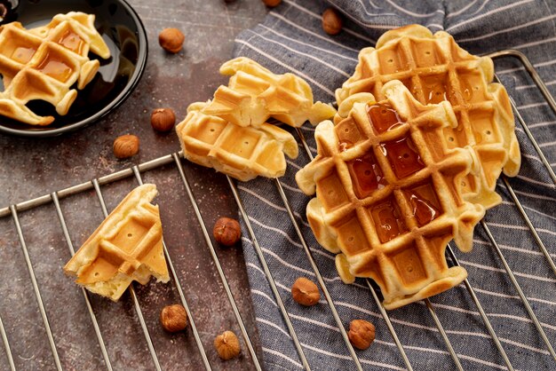 Alto ângulo de mel em cima de waffles com avelãs