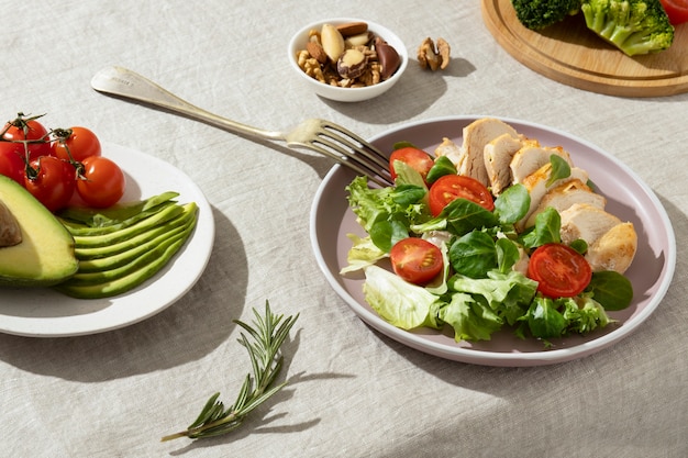 Alto ângulo de prato com comida de dieta ceto e um prato com abacate fatiado