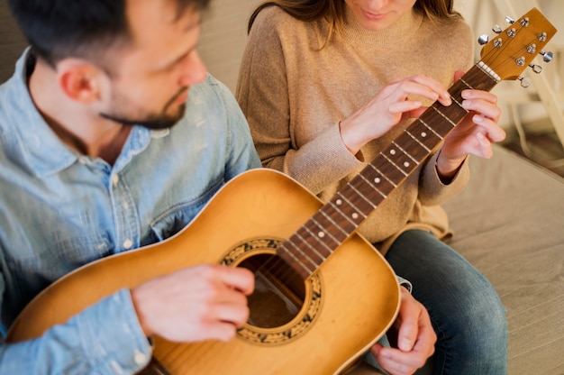 Alto ângulo de professor de violão, tutoria aluno em casa