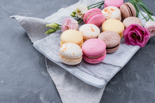 Foto grátis alto ângulo de variedade de macarons com rosas