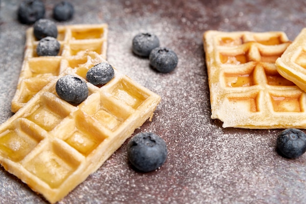 Foto grátis alto ângulo de waffles com mirtilos e açúcar em pó