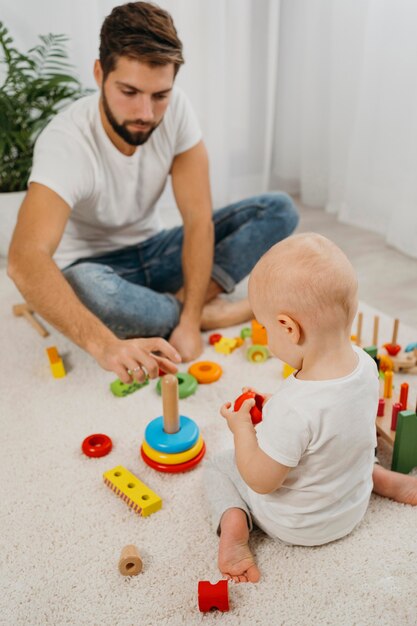 Alto ângulo do pai brincando com o bebê em casa