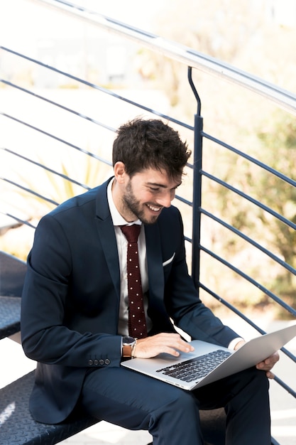 Alto ângulo feliz homem na escada com laptop