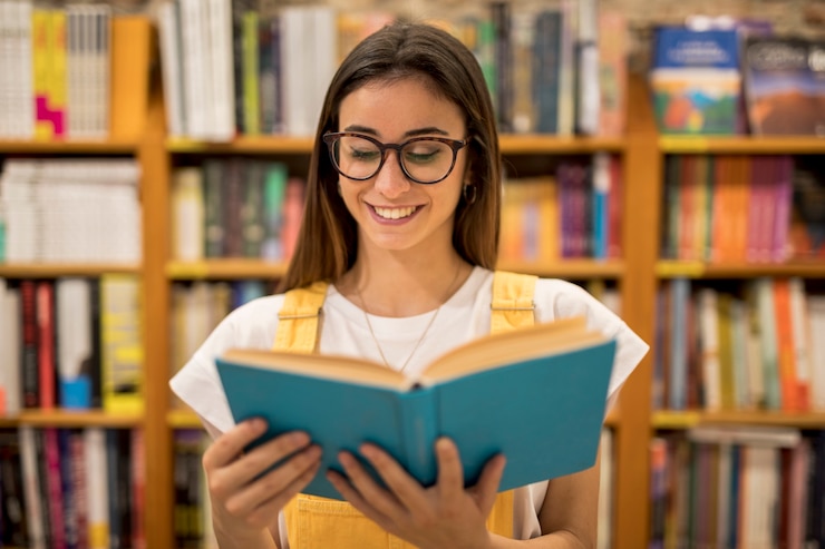 Foto grátis aluna adolescente de óculos a ler um livro.