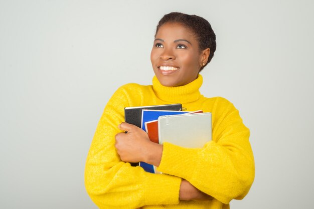 Aluna alegre feliz abraçando livros