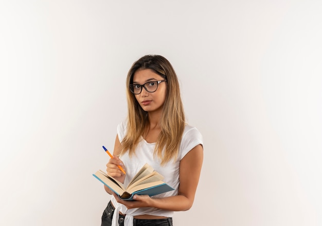 Foto grátis aluna confiante jovem e bonita segurando uma caneta e um livro aberto isolado no branco com espaço de cópia