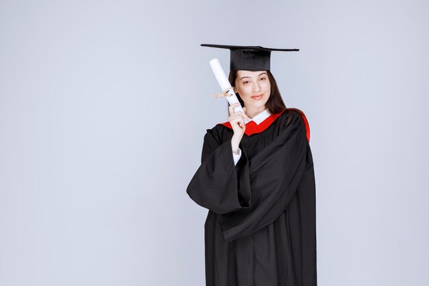 Aluna de pós-graduação em vestido com certificado de faculdade posando. Foto de alta qualidade