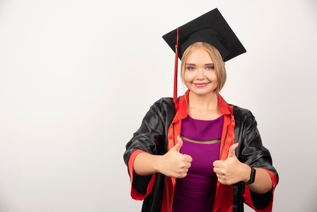 Aluna em um vestido sorrindo enquanto faz os polegares para cima no fundo branco. Foto de alta qualidade