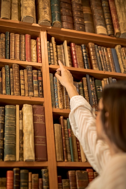 Foto grátis aluna inteligente à procura de livro na biblioteca