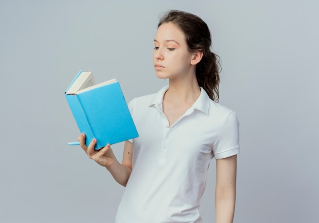 Aluna jovem e bonita segurando e lendo um livro com uma caneta na mão, isolado no fundo branco com espaço de cópia