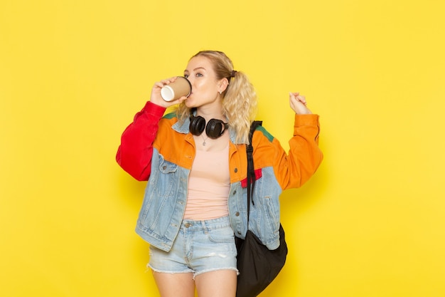 aluna jovem em roupas modernas bebendo café em amarelo