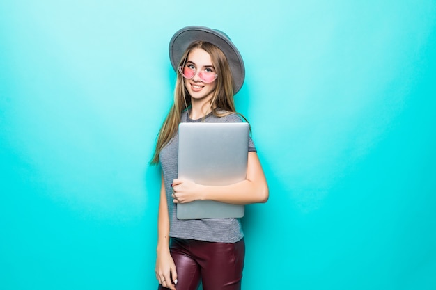 Aluna modelo garota em roupas da moda casuais trabalha relógios em seu laptop isolado no verde